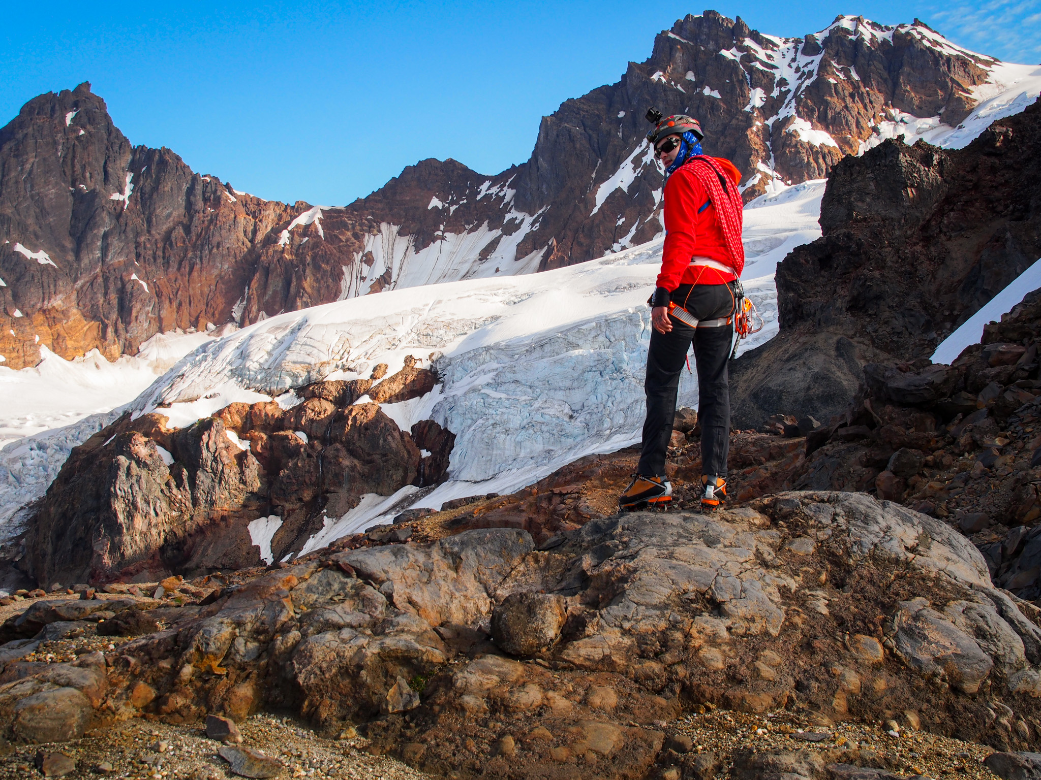 Mountaineer on rocks with glacier behind