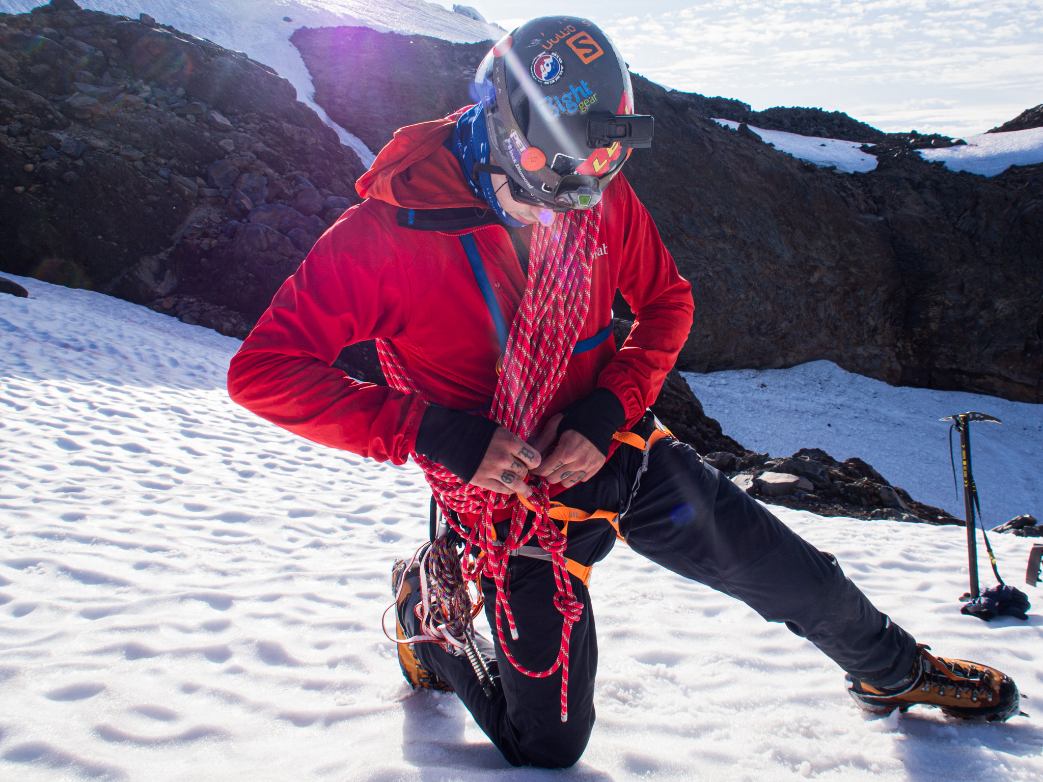 Mountaineer coiling rope on snow